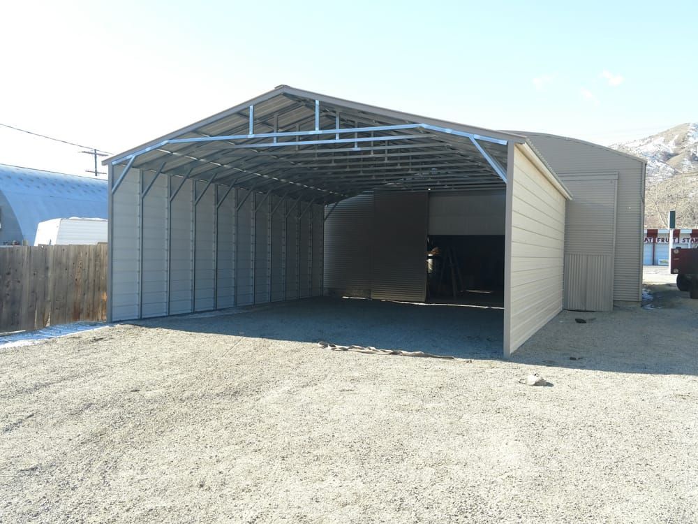 A large garage with a sliding door is sitting in the middle of a gravel lot.