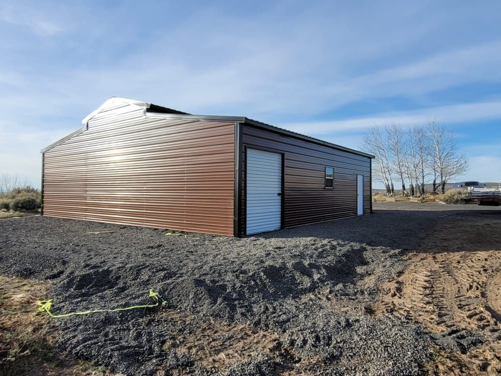 A large metal building is sitting in the middle of a dirt field.