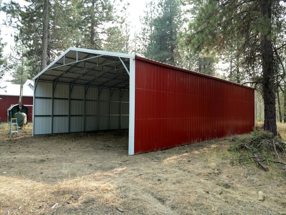 A red and white barn is sitting in the middle of a dirt field.