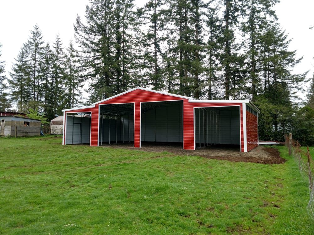 A red barn is sitting in the middle of a grassy field.