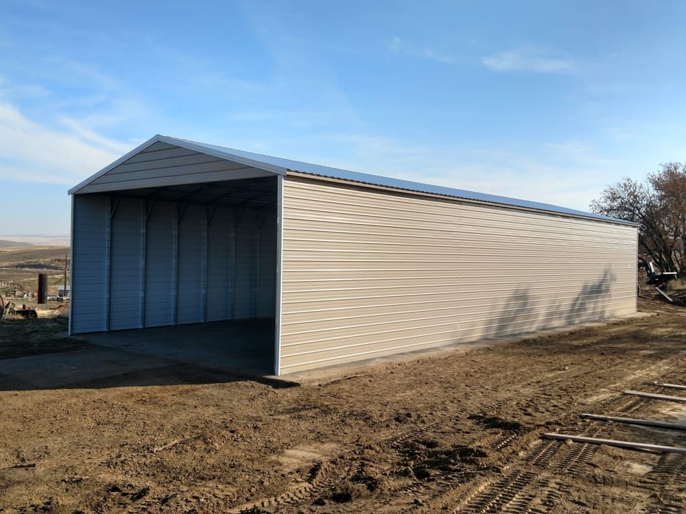 A metal garage is sitting in the middle of a dirt field.
