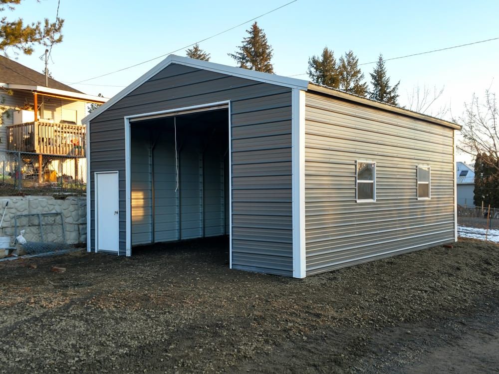 A metal garage with a white door is sitting on top of a dirt hill.