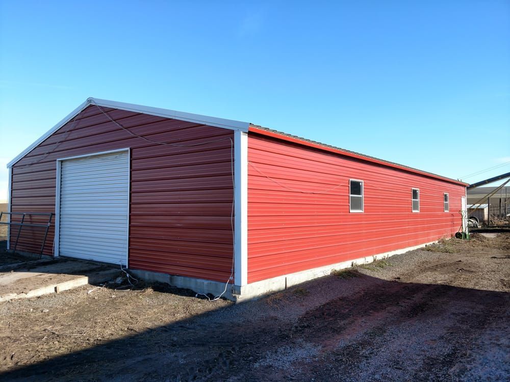 A red metal building with a white garage door and windows.