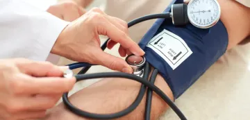 Ein Arzt misst den Blutdruck eines Patienten mit einer Blutdruckmanschette und einem Stethoskop.