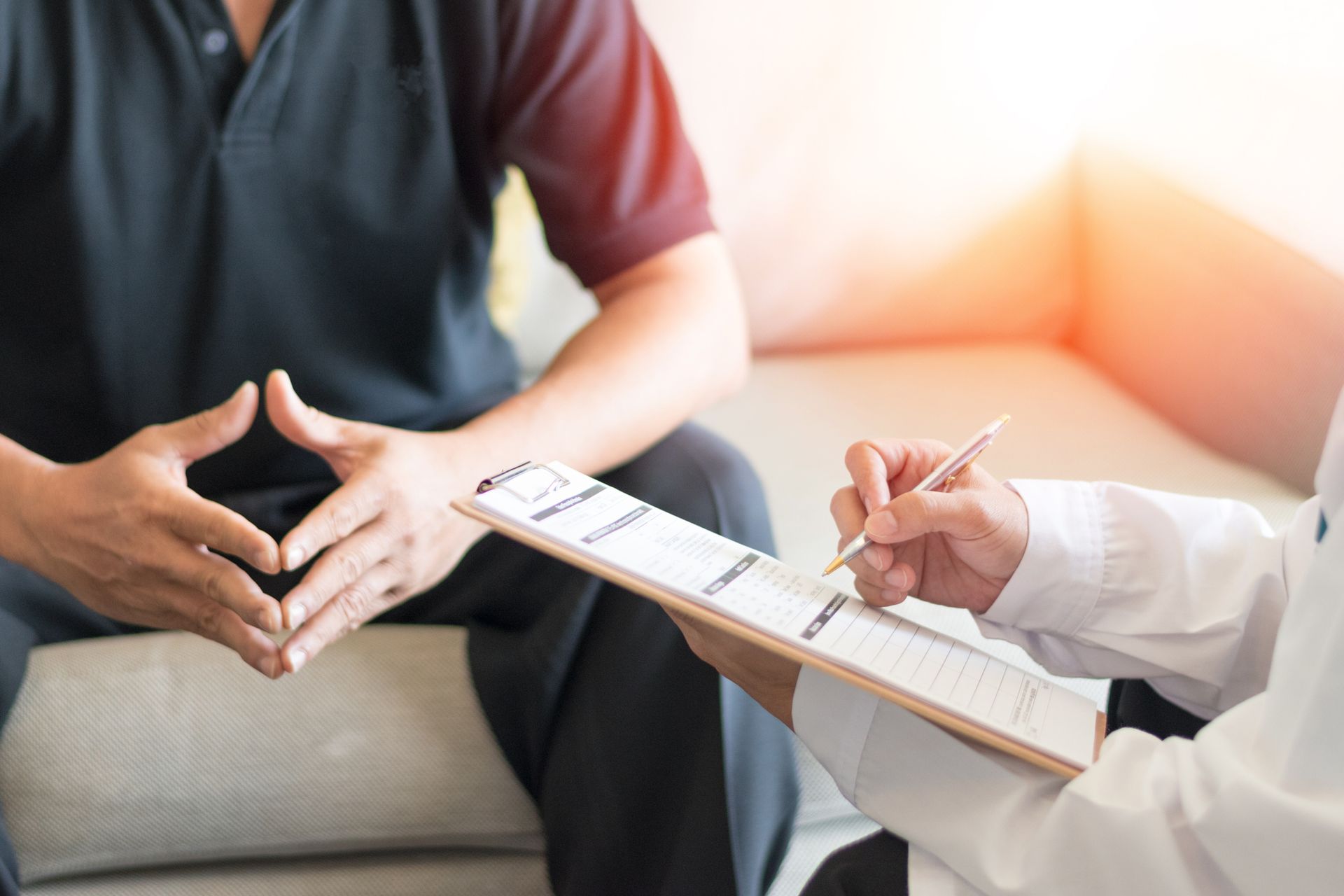 A doctor is talking to a patient while holding a clipboard.