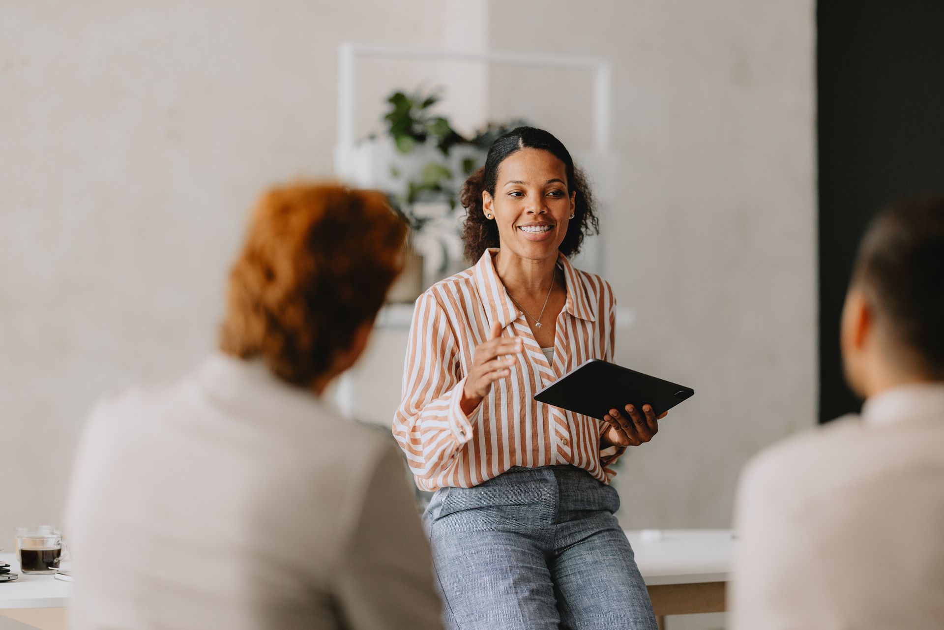 A woman is sitting at a table giving a presentation to a group of people.