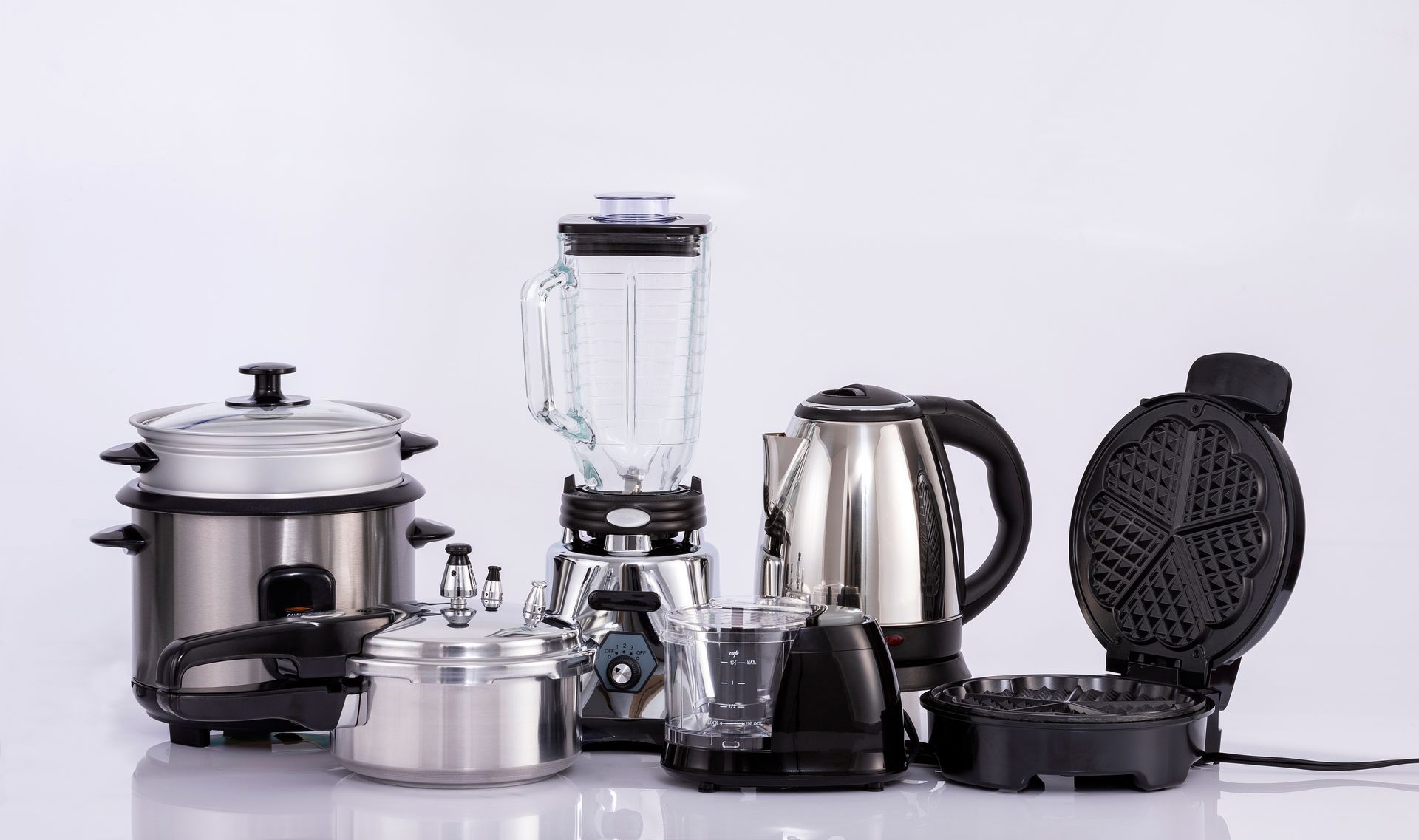 A group of kitchen appliances including pots , blenders , kettles , and waffles.