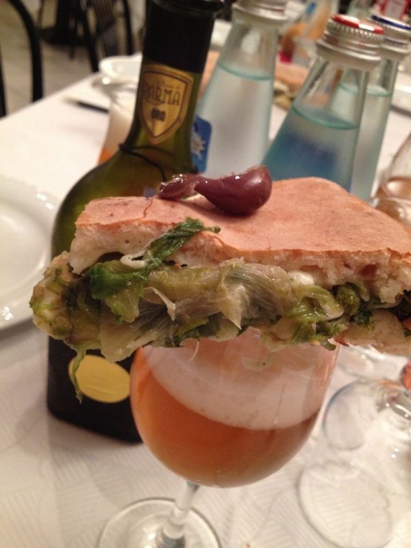 Un panino è appoggiato su un bicchiere di vino.