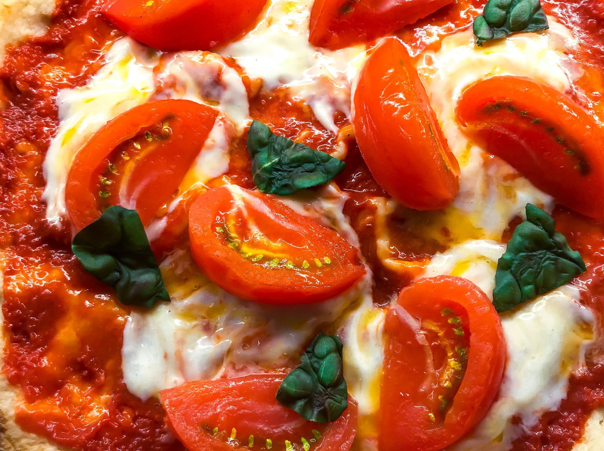 Un primo piano di una pizza con pomodori e basilico sopra.