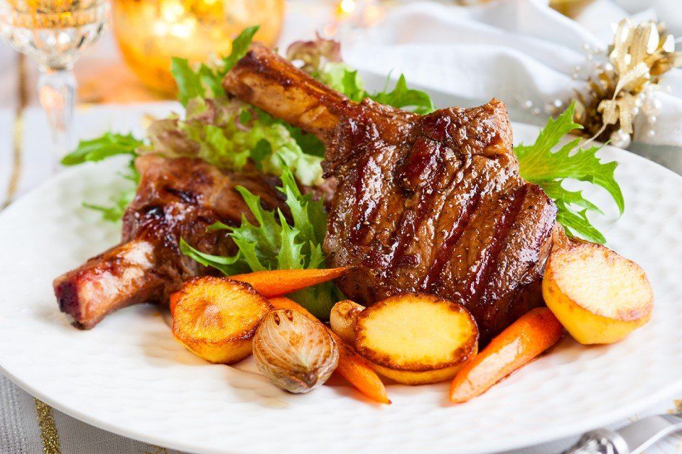 Un piatto bianco con sopra carne, patate, carote e lattuga.