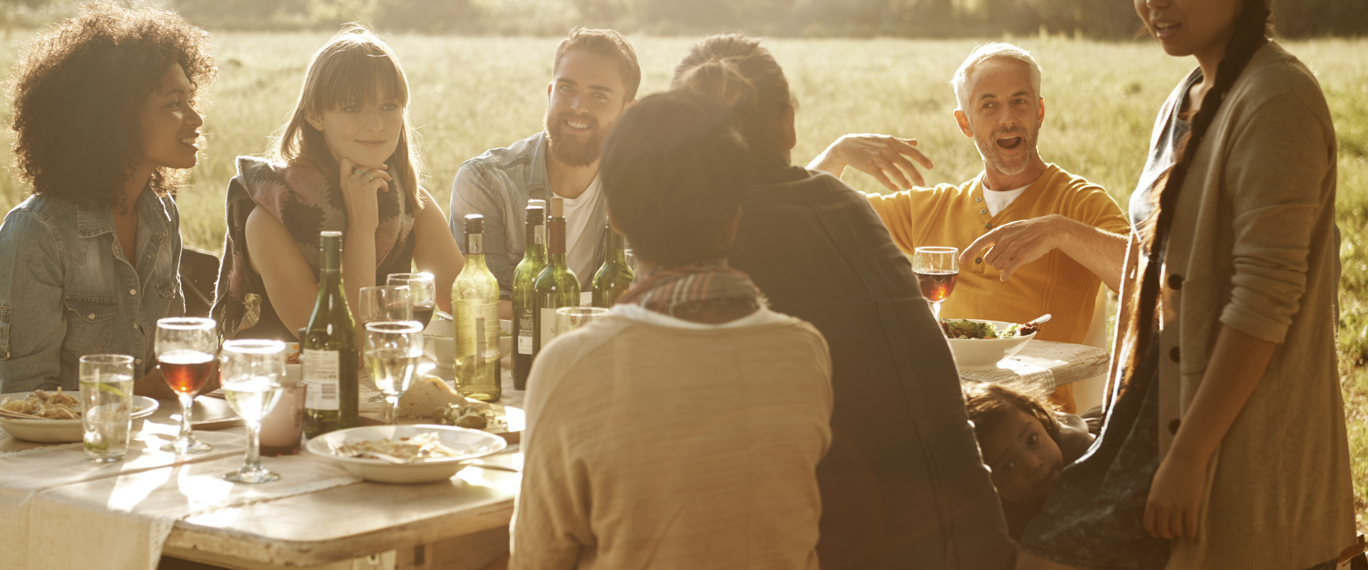 A group of people are sitting around a table in a field.