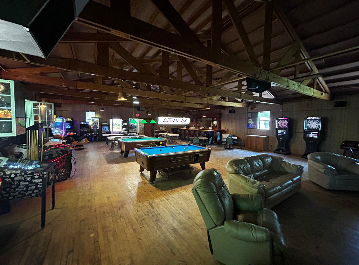 A large room with a lot of pool tables and chairs