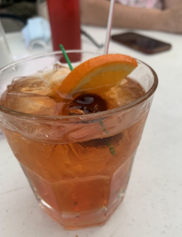 A close up of a glass of orange juice with a cherry on top.