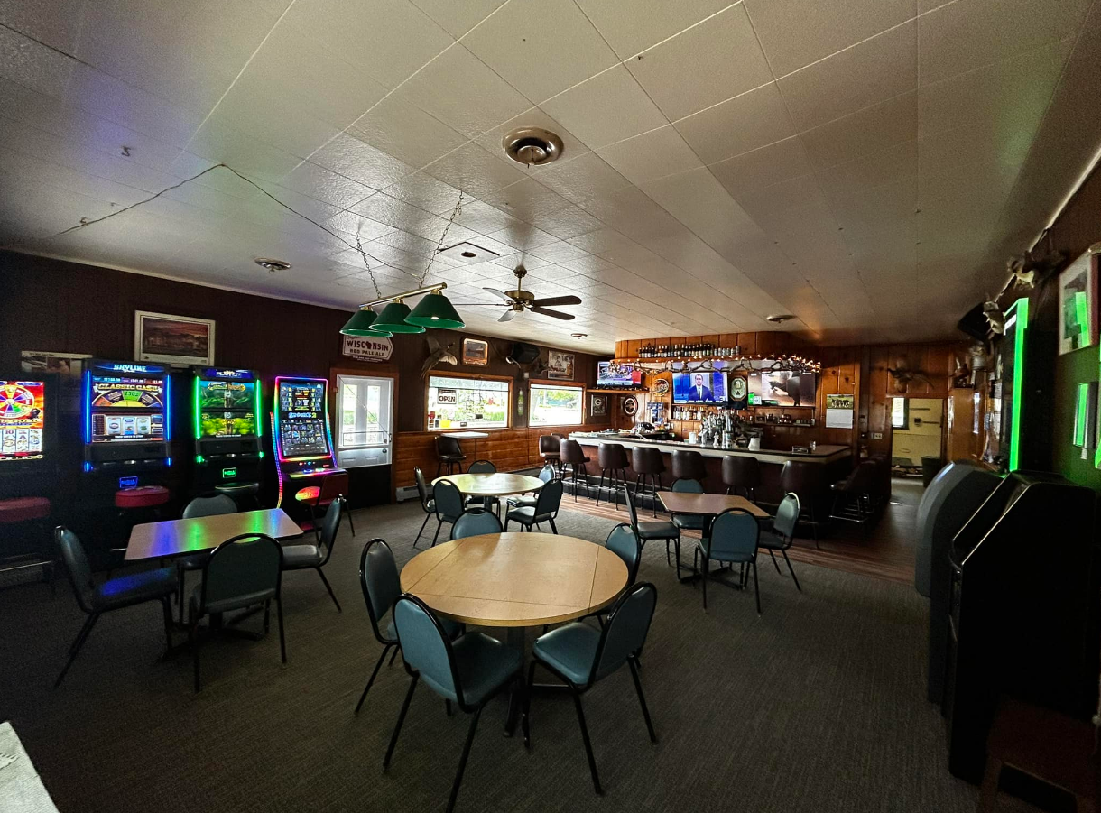 A large room with tables and chairs and a bar.
