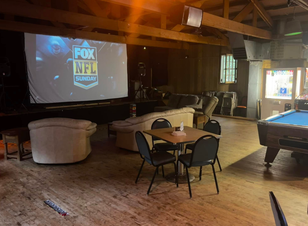 A room with a pool table and a large screen that says fox nfl on it.