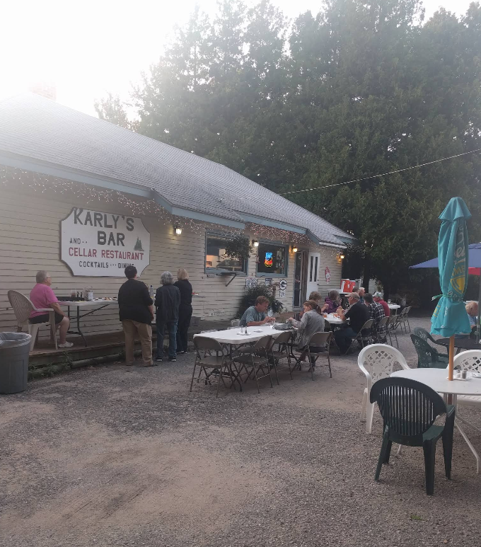 A group of people are sitting at tables outside of a building.