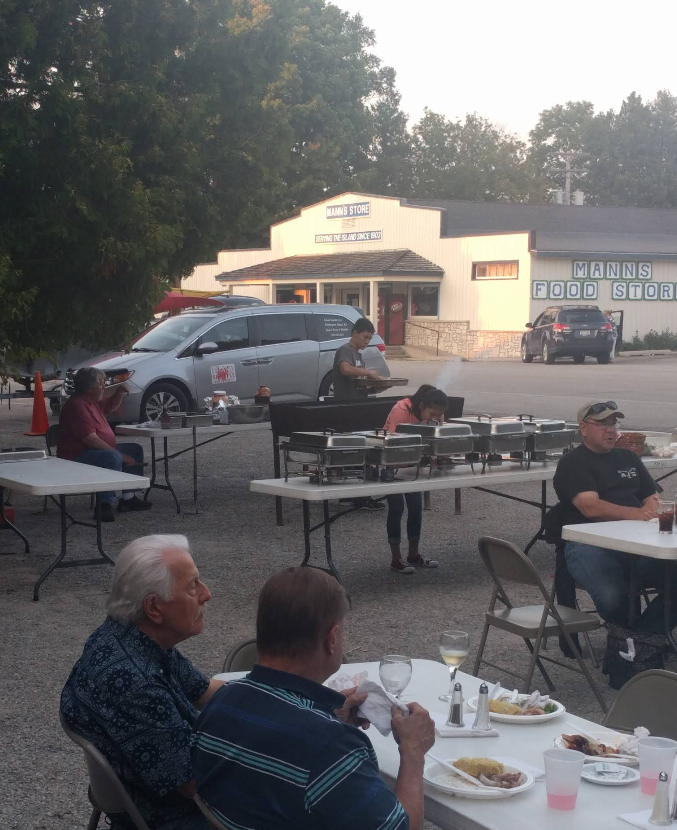 A group of people are sitting at tables in front of a building that has the word buffet on it