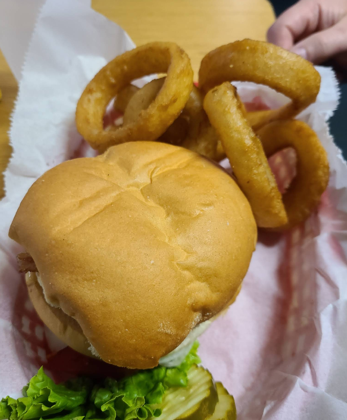 A hamburger with lettuce and onion rings in a basket