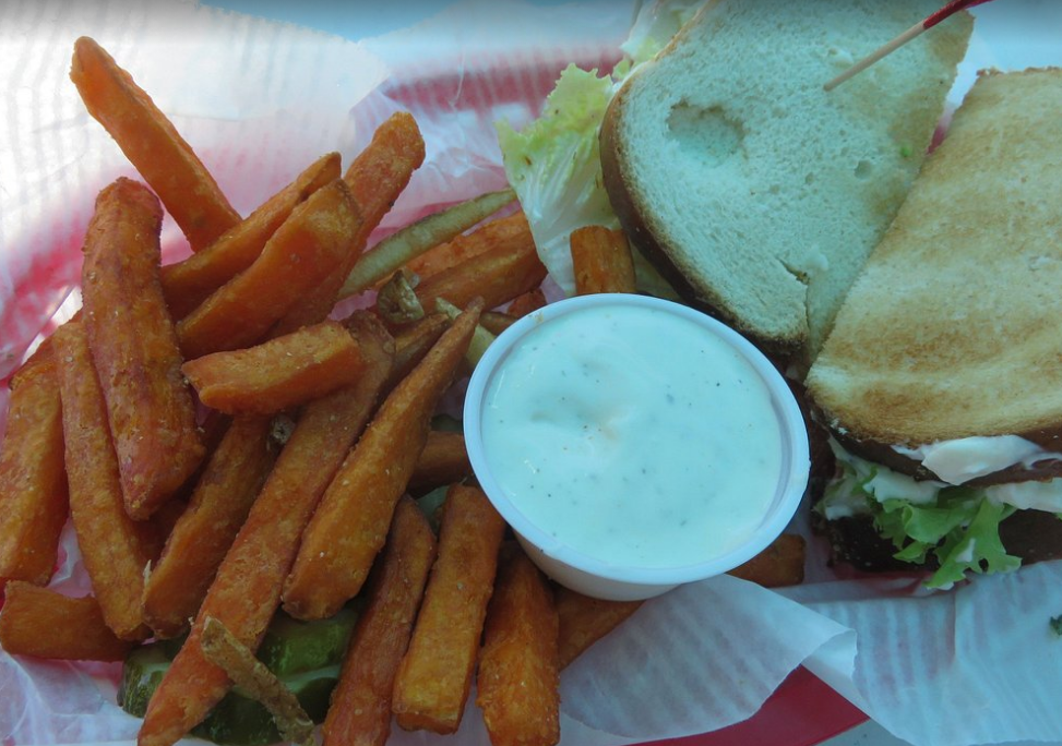 A sandwich with sweet potato fries and ranch dressing