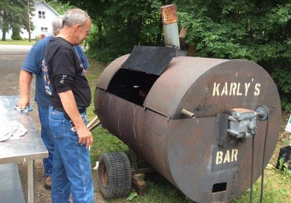 Two men standing next to a large barrel that says karly 's bar
