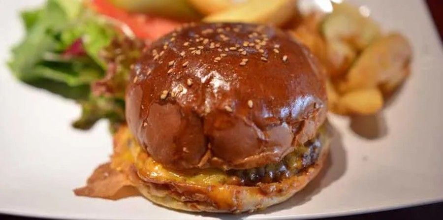 Closeup of a cheeseburger on a plate with salad and fries.