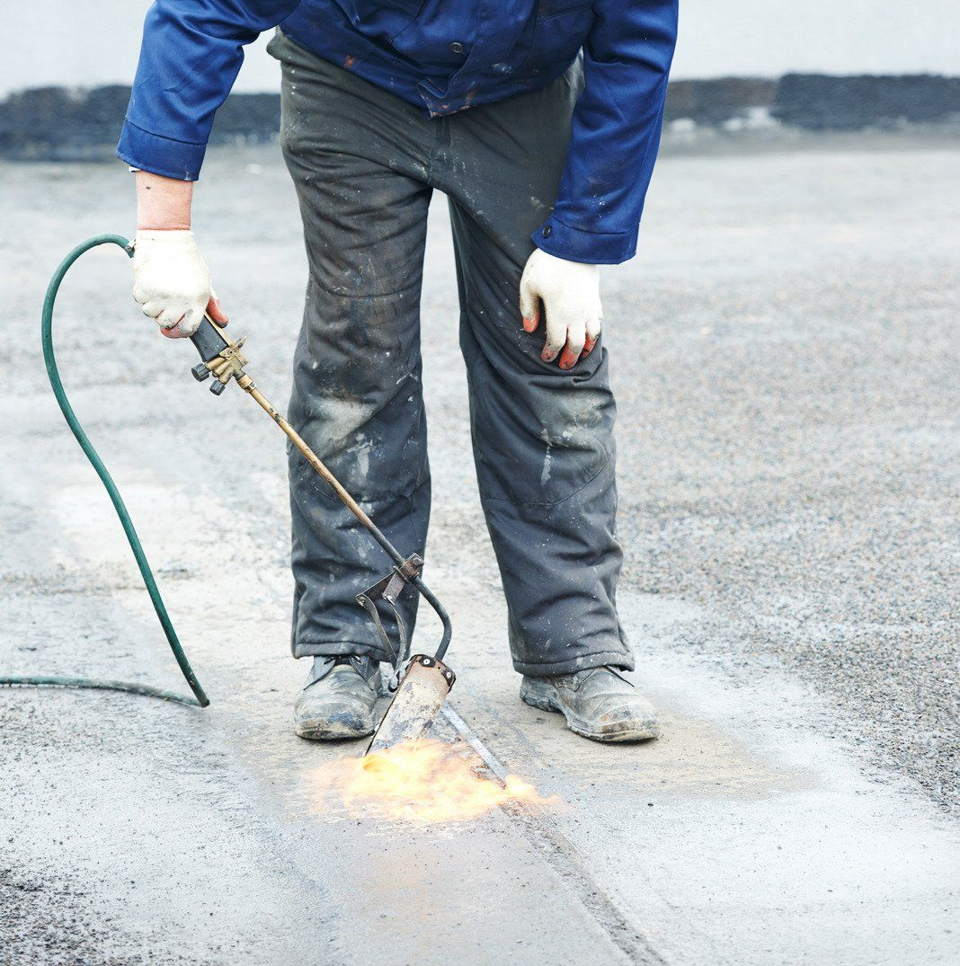 Two electricians working on an electrical panel outside a building. One holds a cable.