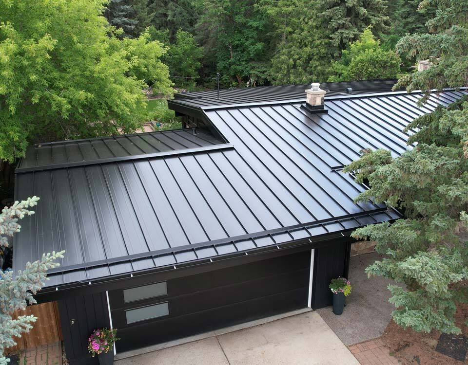 Two electricians working on an electrical panel outside a building. One holds a cable.