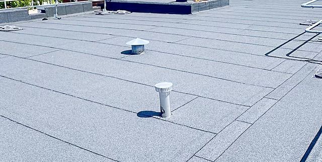 Two electricians working on an electrical panel outside a building. One holds a cable.
