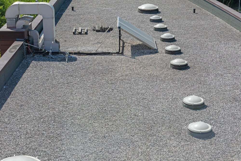 Two electricians working on an electrical panel outside a building. One holds a cable.