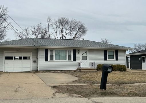 White house with gray roof, black shutters, and attached garage. A mailbox is in the front yard.