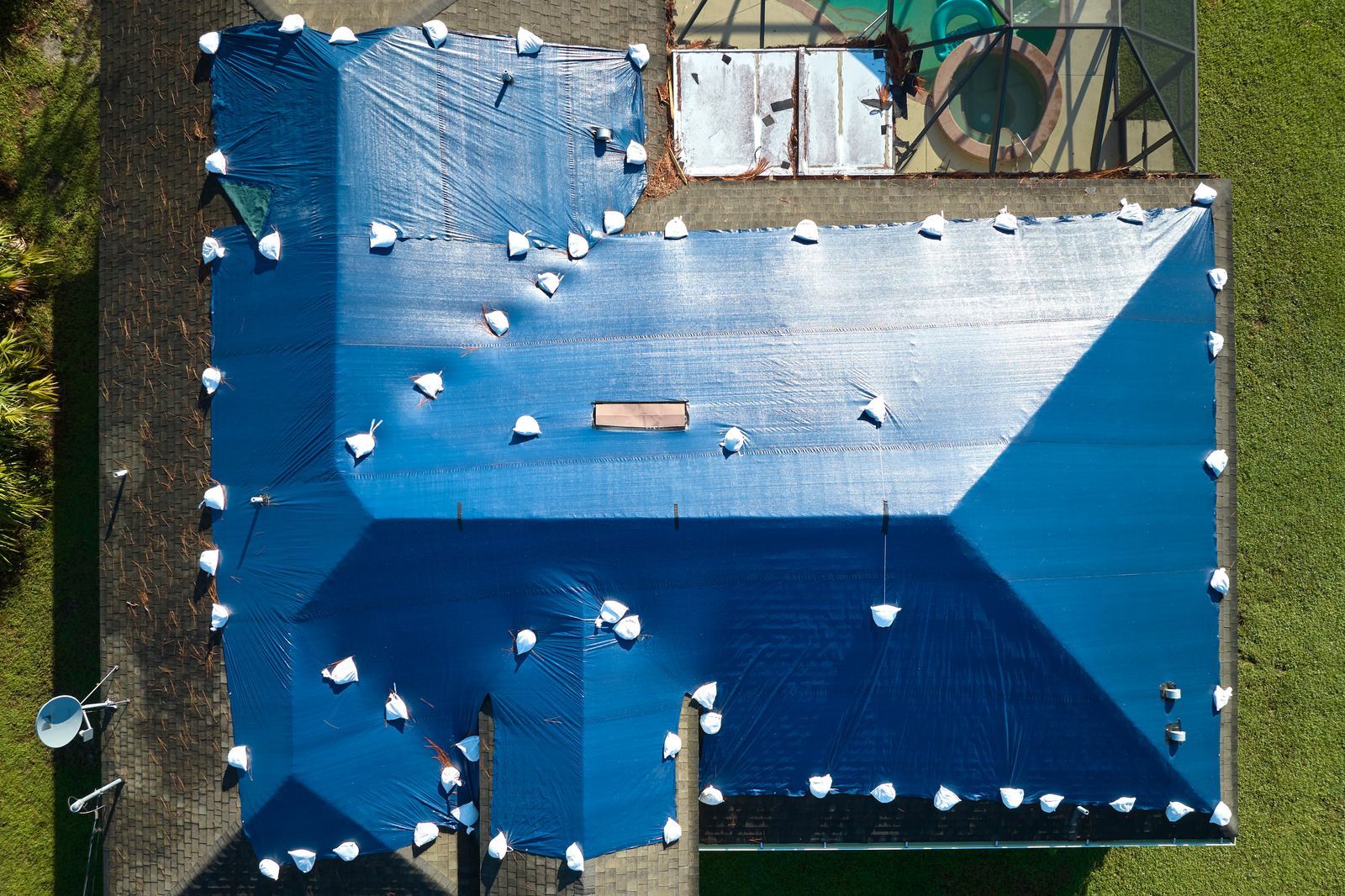 Two electricians working on an electrical panel outside a building. One holds a cable.
