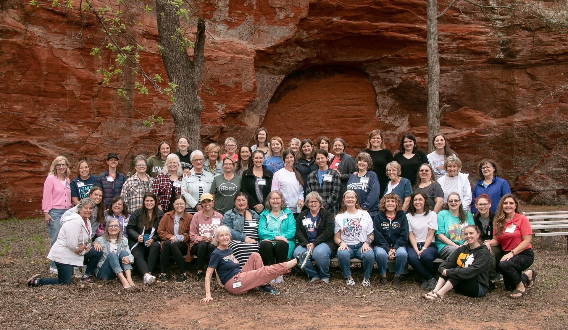 A large group of people are posing for a picture in front of a rock formation.