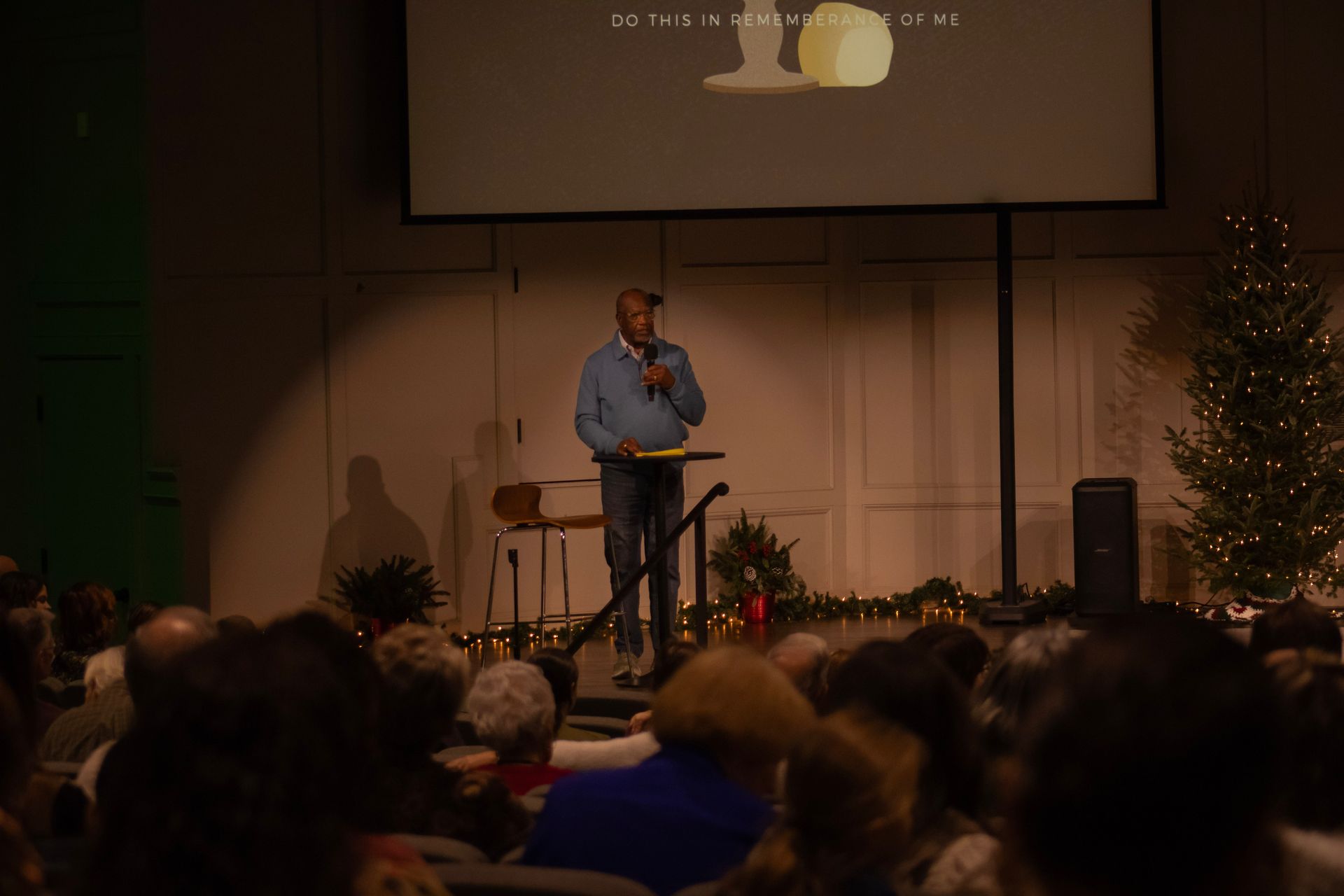 A man is standing at a podium giving a speech in front of a crowd.