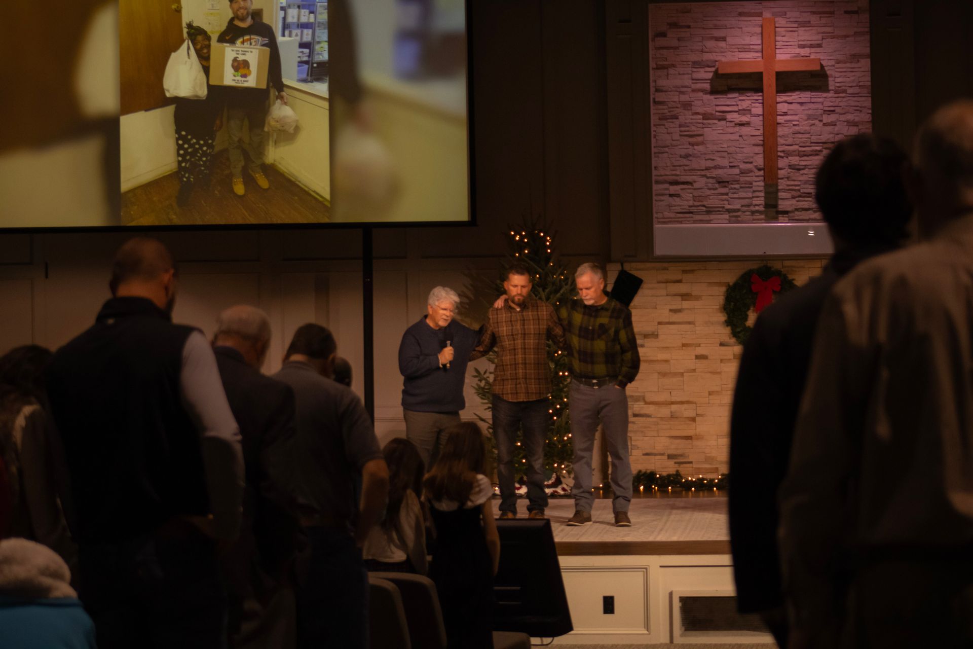 A group of people are standing in front of a large screen in a church.