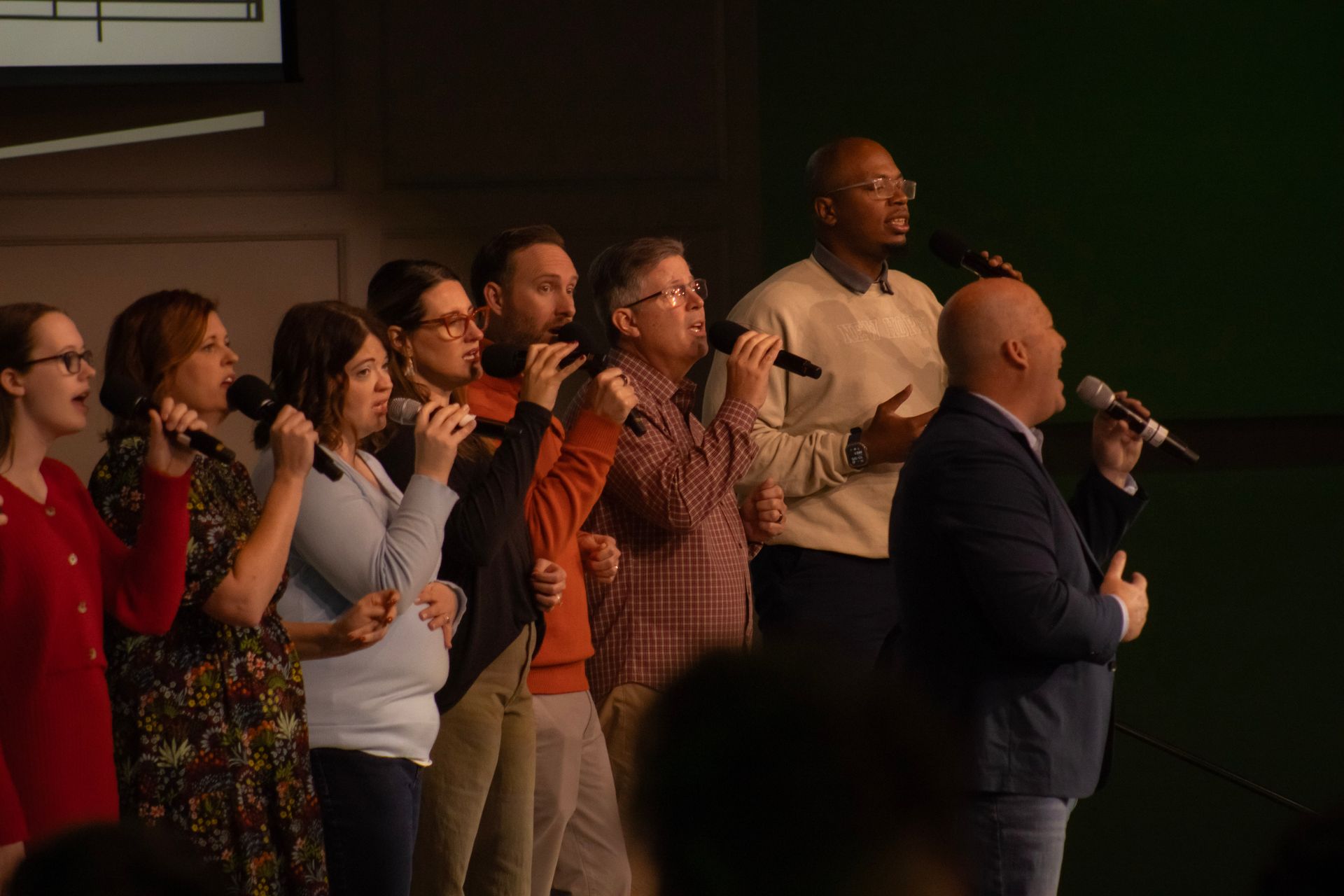 A group of people are singing into microphones on a stage.