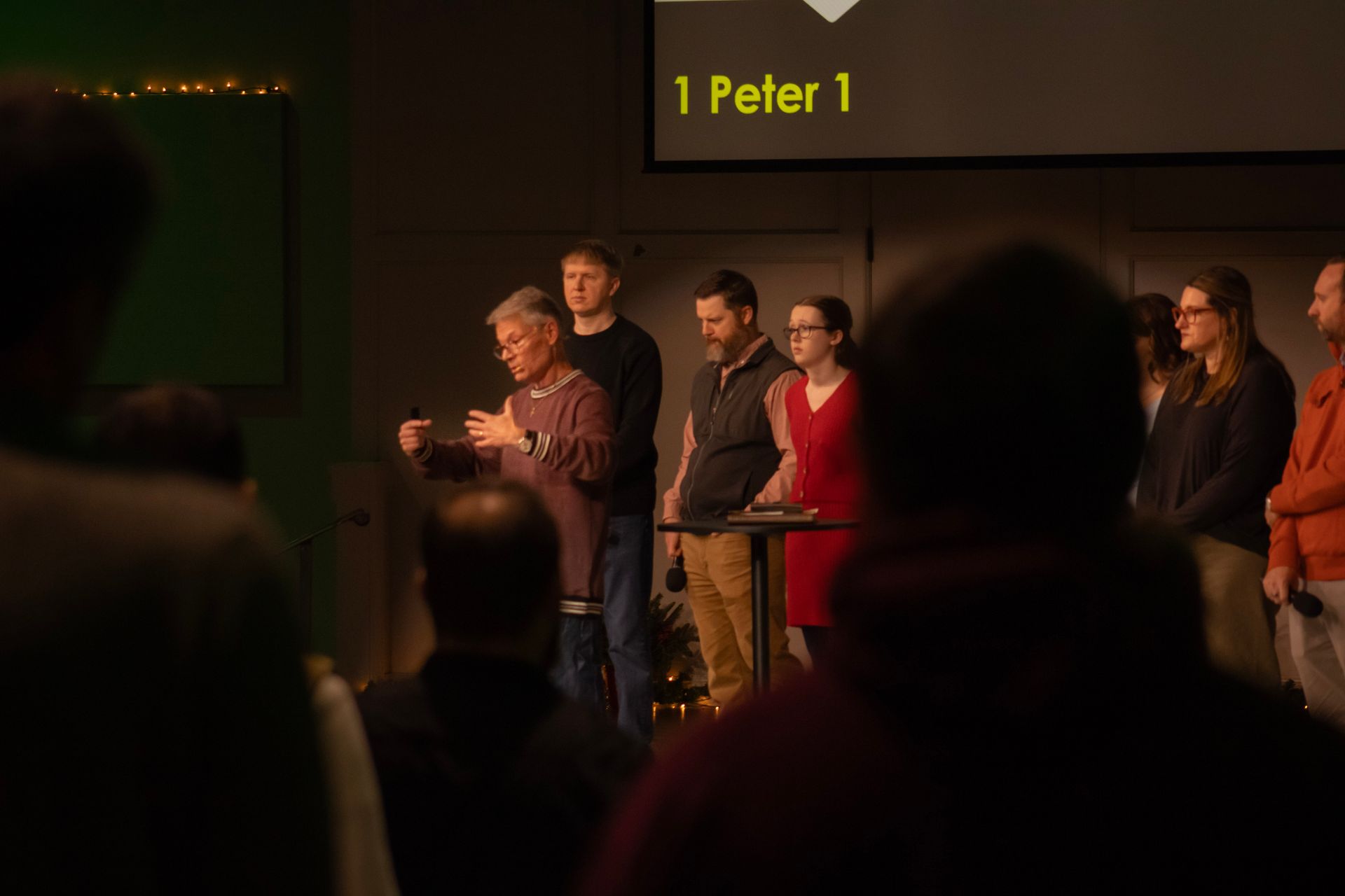 A group of people are standing in front of a projector screen.