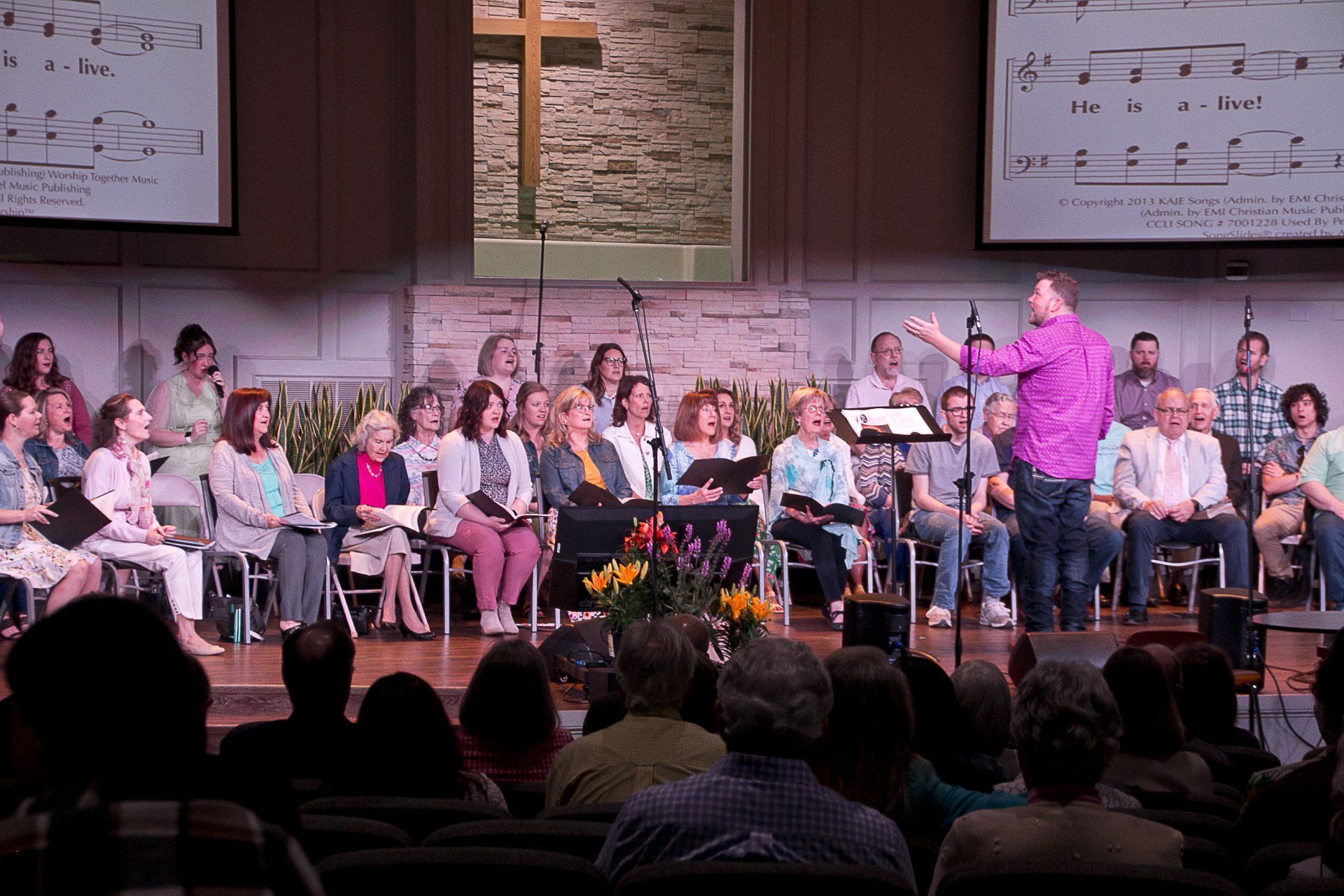A man is standing in front of a large choir in a church.