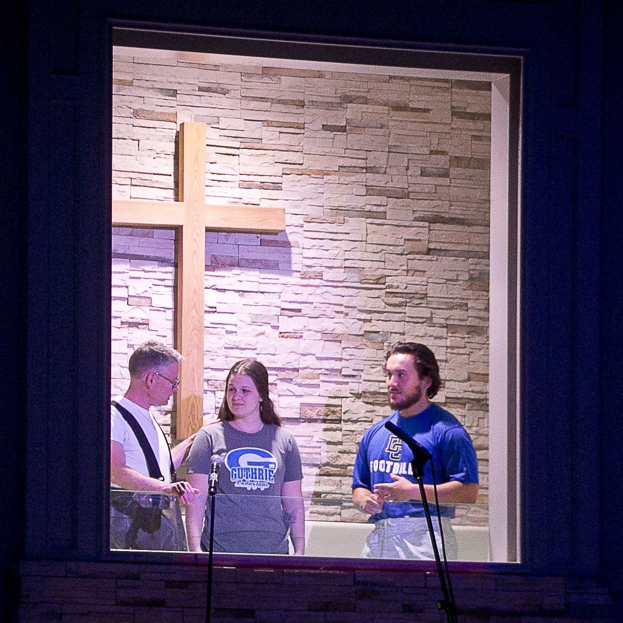 A group of people are standing in front of a cross in a church.