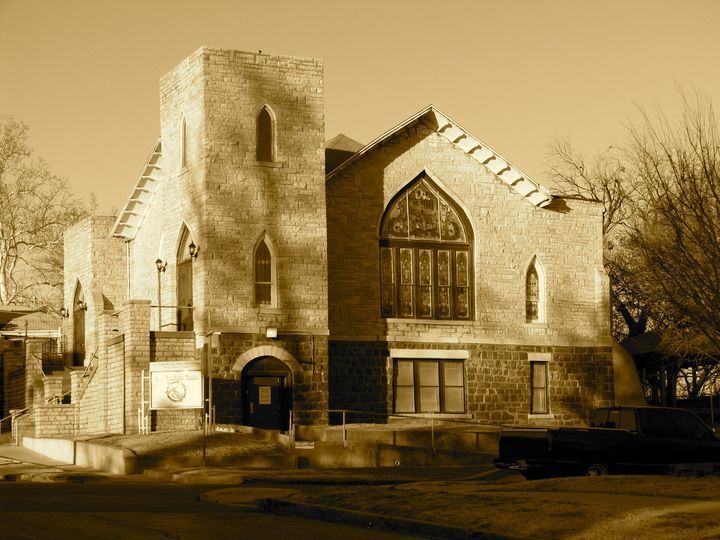 A sepia toned photo of a church with a truck parked in front of it