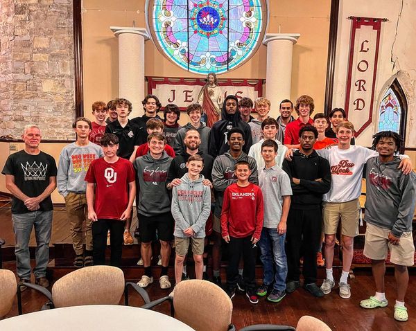 A group of young men are posing for a picture in front of a stained glass window.