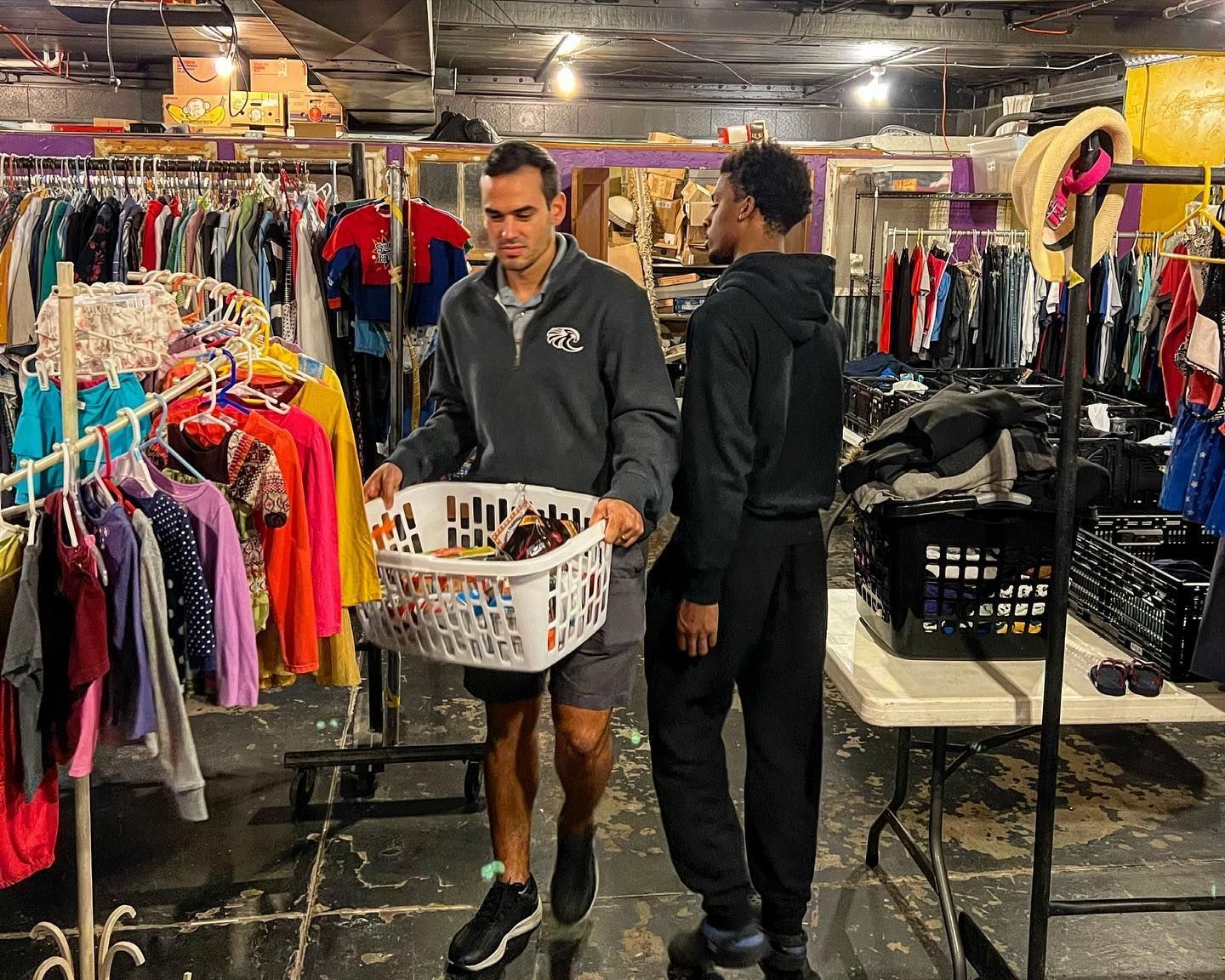 A man is carrying a basket of clothes in a store.