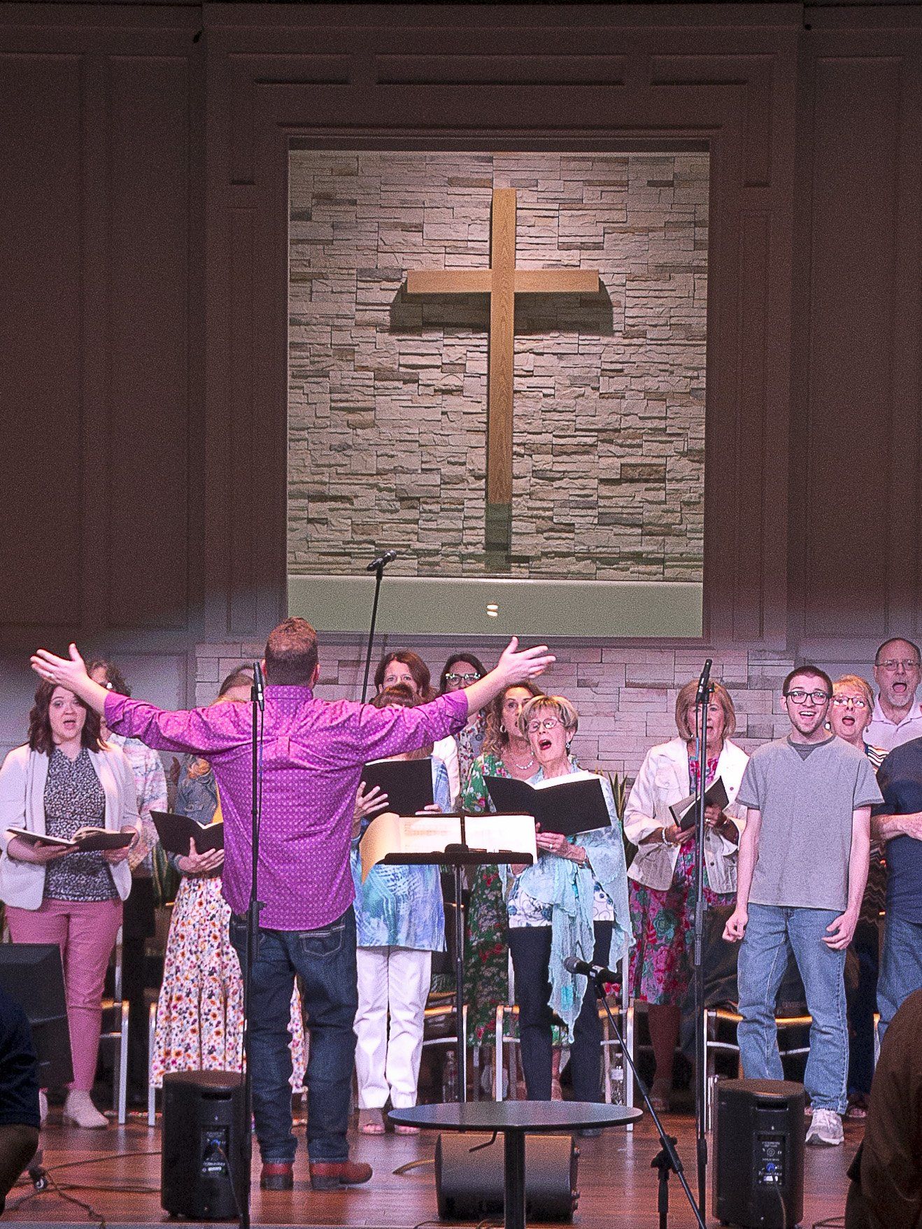 A group of people singing in front of a cross in a church