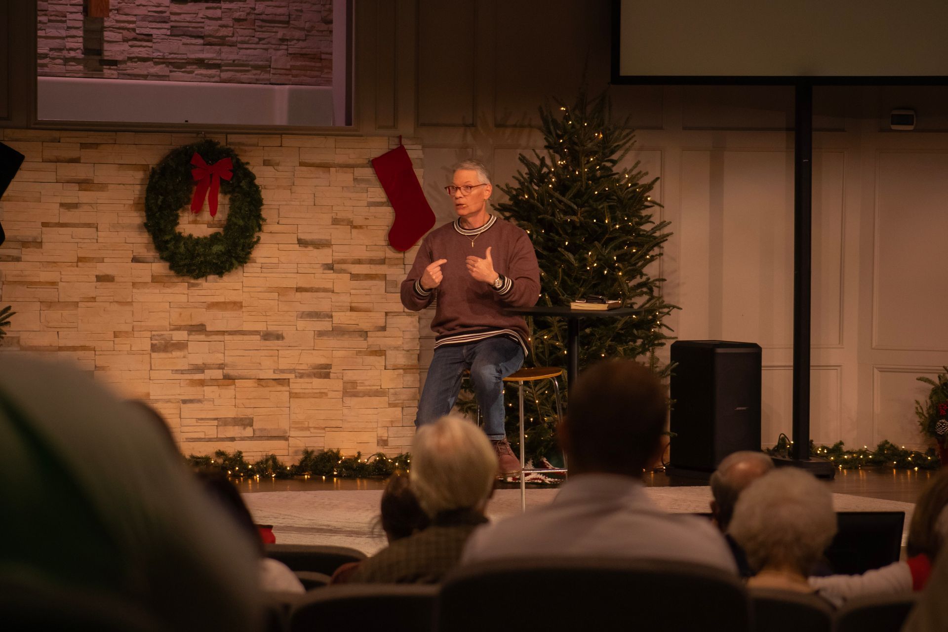 A man is giving a speech in front of a christmas tree in a church.