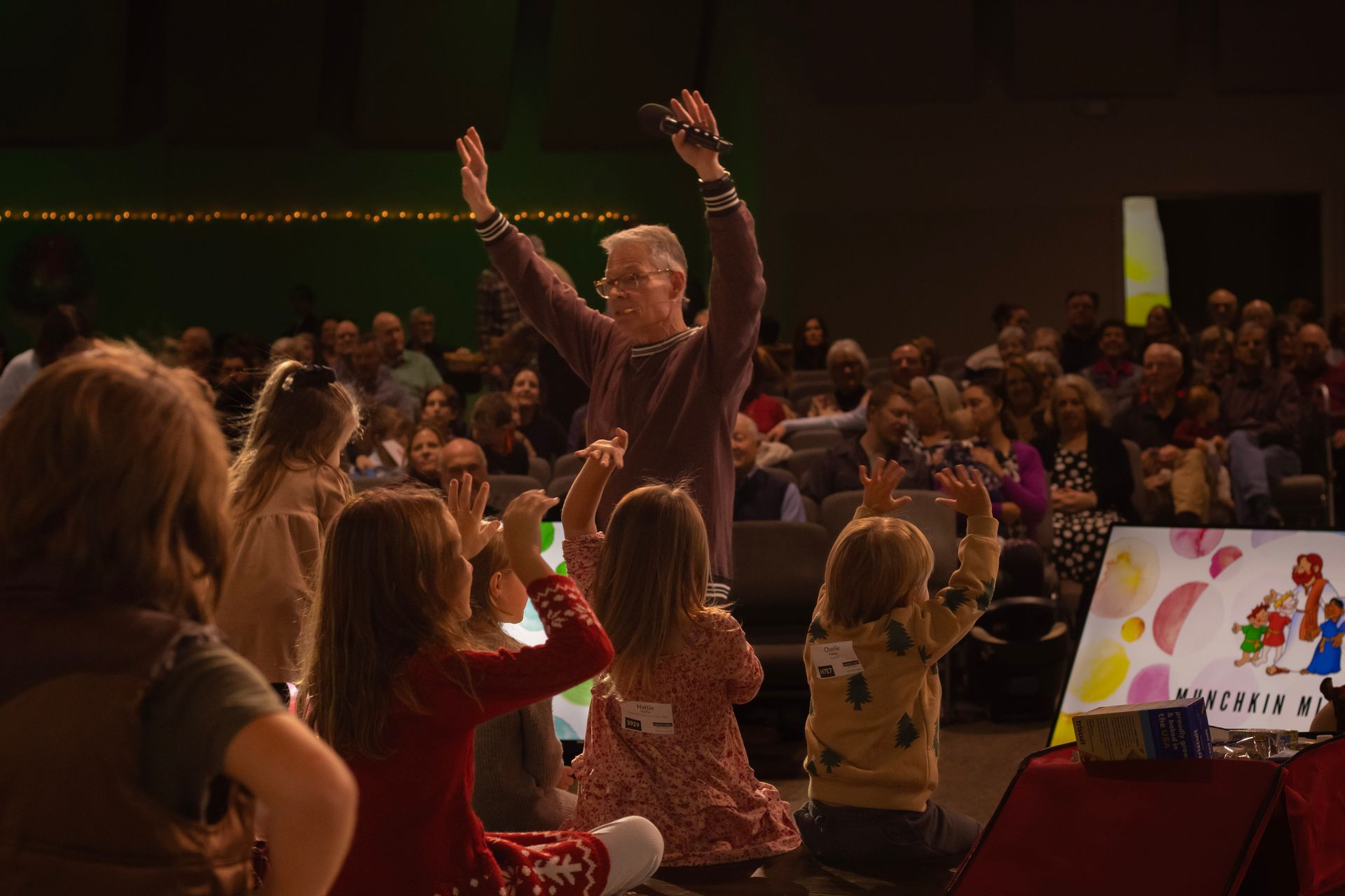 A man is standing in front of a crowd of people with his arms in the air.