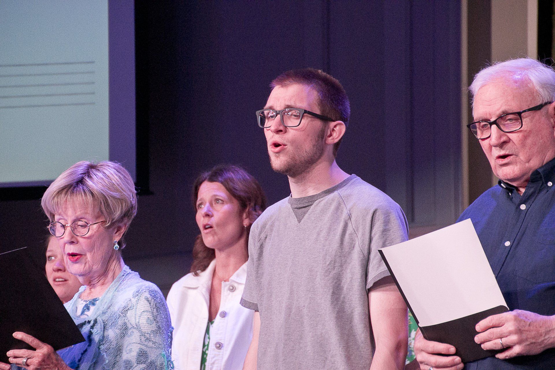 A group of people are singing together on a stage.