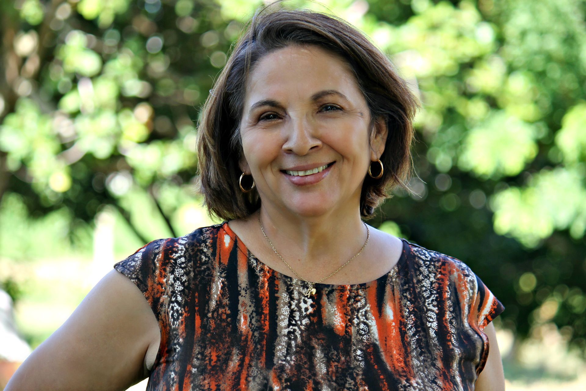 A woman in an orange and black dress is smiling for the camera.