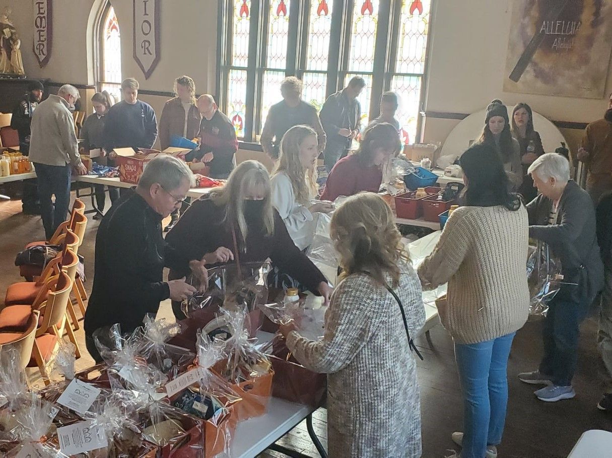 A group of people are standing around tables in a room.