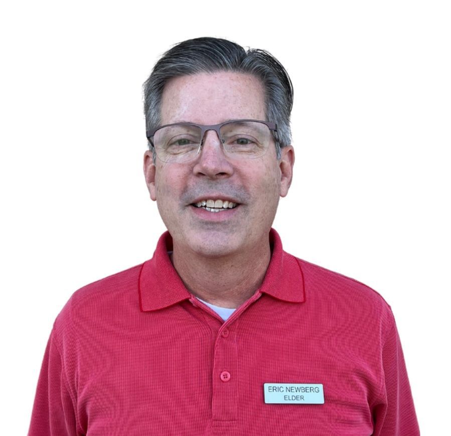 A man wearing glasses and a suit and tie is smiling for the camera.