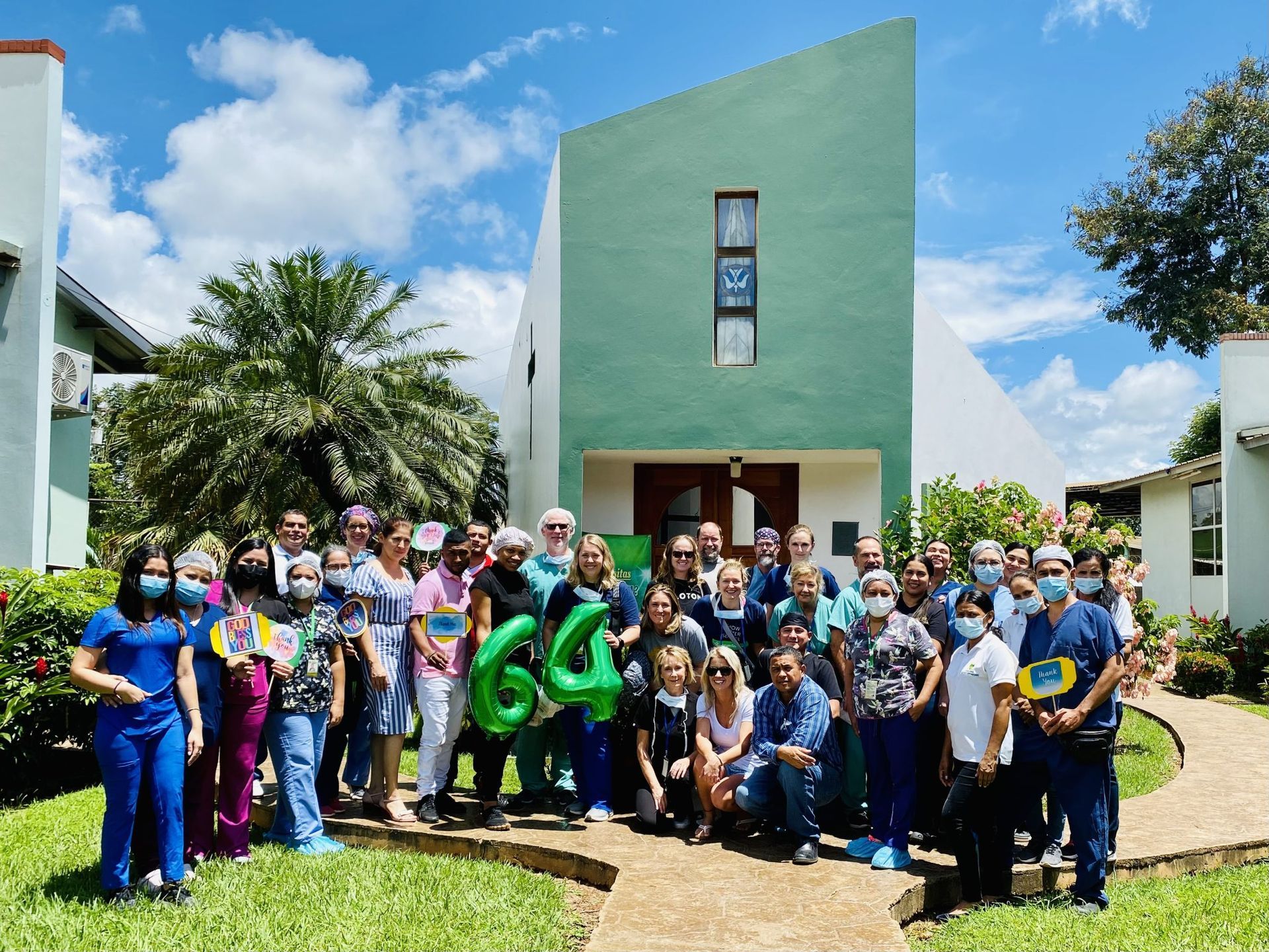 A group of people are posing for a picture in front of a green building.