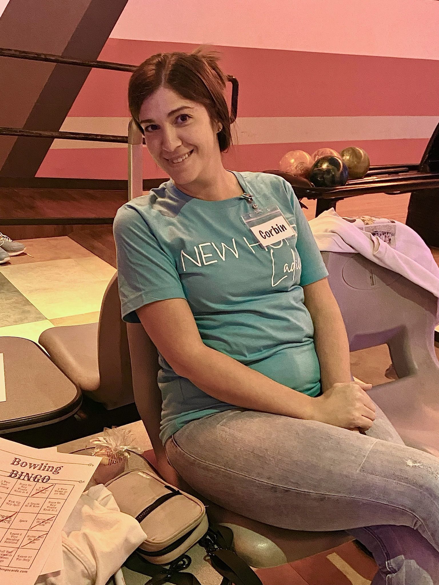 A woman in a blue shirt is sitting in a bowling alley